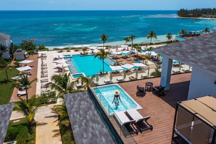 Woman standing in pool on rooftop terrace staring out at the ocean surrounding Excellence Oyster Bay